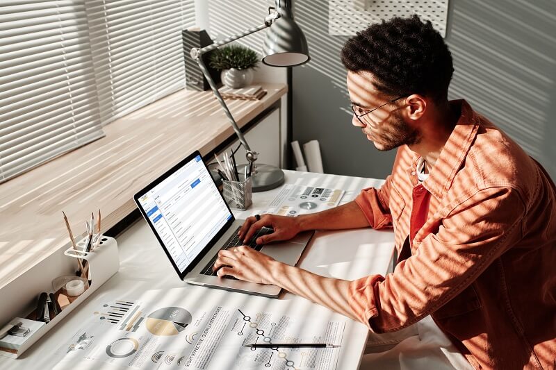 Man writing a factual dispute letter on a laptop while reviewing credit report documents